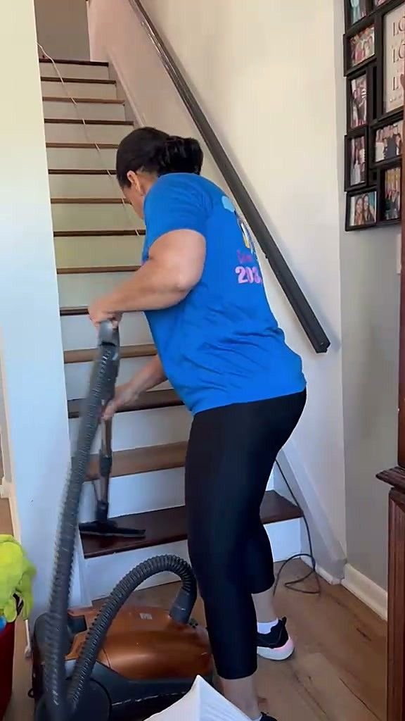 A uniformed team member vacuuming fine dust from a staircase