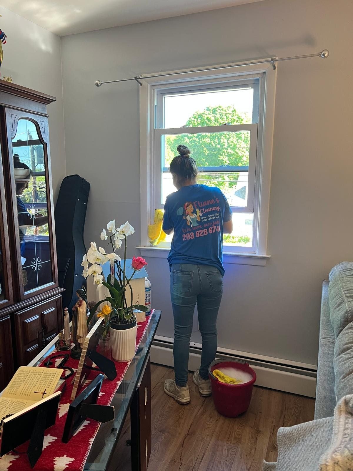 A uniformed team member cleaning a window in a client home